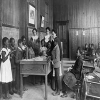 Afroamerička djeca koja pričaju o danu zahvalnosti s maketom brvnare na stolu, Osnovna škola Ouittier, Hampton,